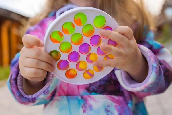 Pop-lo brinquedo fidget em mãos de menina. colorido antistress crianças brinquedo fidget. — Fotografia de Stock