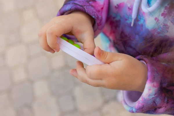 Doe het viooltje in de handen van een meisje. Kleurrijke antistress kinderen speelgoed fidget. — Stockfoto