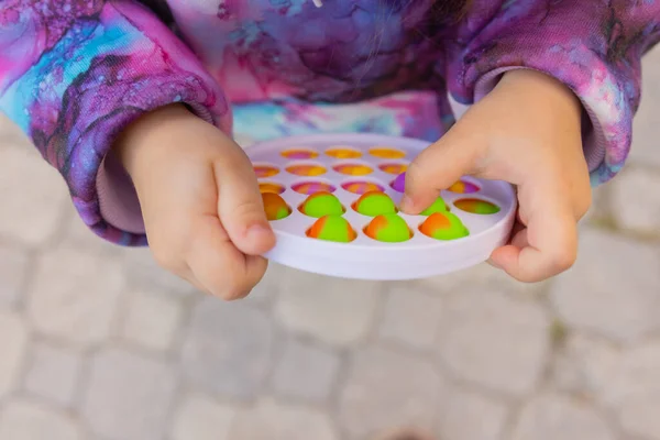 Pop-lo brinquedo fidget em mãos de menina. colorido antistress crianças brinquedo fidget. — Fotografia de Stock