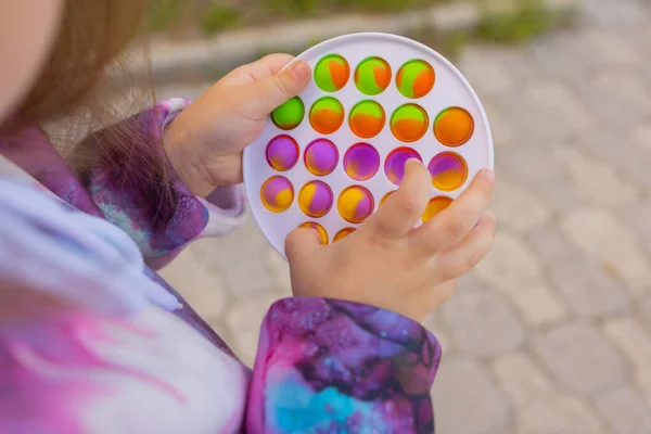 Pop-lo brinquedo fidget em mãos de menina. colorido antistress crianças brinquedo fidget. — Fotografia de Stock