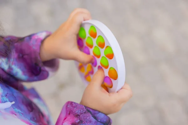 Pop-lo brinquedo fidget em mãos de menina. colorido antistress crianças brinquedo fidget. — Fotografia de Stock