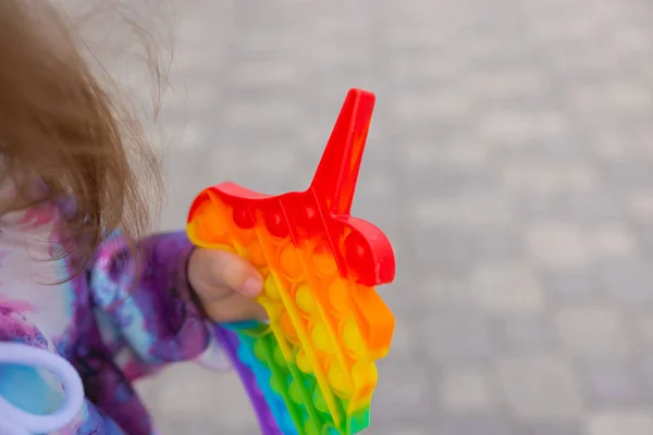 Pop it fidget juguete en manos de chica. Colorido antiestrés niños juguete fidget. — Foto de Stock
