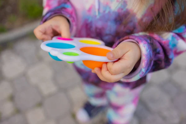 Doe het viooltje in de handen van een meisje. Kleurrijke antistress kinderen speelgoed fidget. — Stockfoto