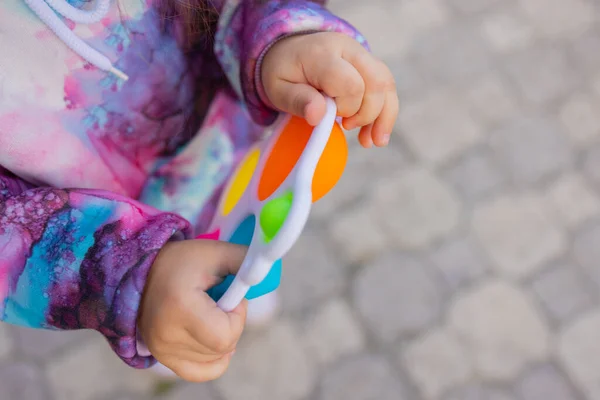 Pop itu fidget mainan di tangan gadis. Anak-anak antistres berwarna mainan gelisah. — Stok Foto