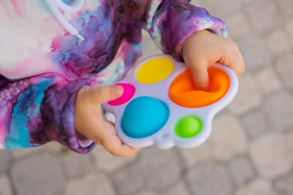 Pop-lo brinquedo fidget em mãos de menina. colorido antistress crianças brinquedo fidget. — Fotografia de Stock