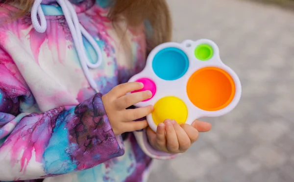 Doe het viooltje in de handen van een meisje. Kleurrijke antistress kinderen speelgoed fidget. — Stockfoto