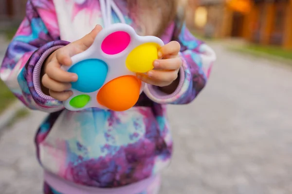 Pop itu fidget mainan di tangan gadis. Anak-anak antistres berwarna mainan gelisah. — Stok Foto