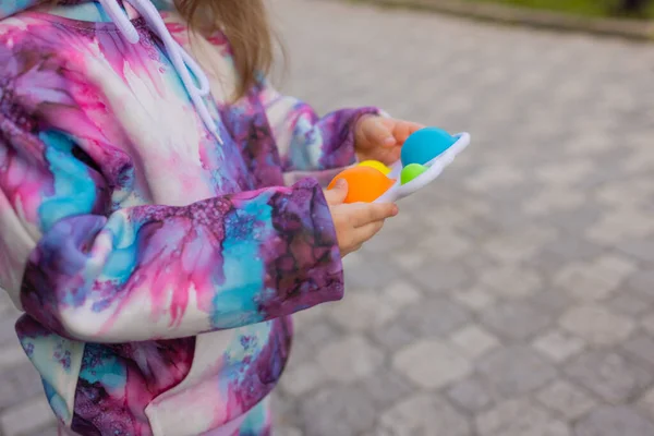 Pop it fidget jouet dans les mains des filles. Jouet anti-stress coloré pour enfants violon. — Photo