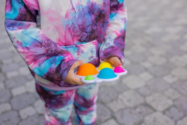 Doe het viooltje in de handen van een meisje. Kleurrijke antistress kinderen speelgoed fidget. — Stockfoto