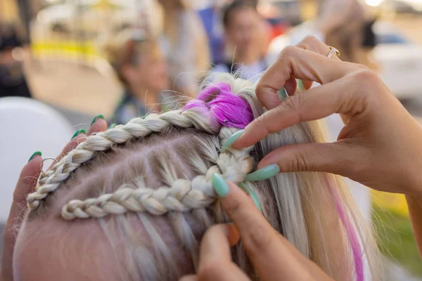 As mãos de mulheres tecem um pigtail na cabeça de morenas. — Fotografia de Stock