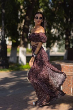 Parkta gözlüklü güzel genç bir kadın yeşilliğin arka planında.