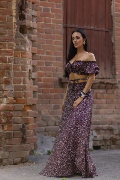 Uma mulher caucasiana com um vestido de polca pontilhado e óculos de sol encostados à parede. — Fotografia de Stock