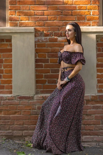 Una mujer caucásica con un vestido de lunares y gafas de sol apoyadas en la pared. — Foto de Stock