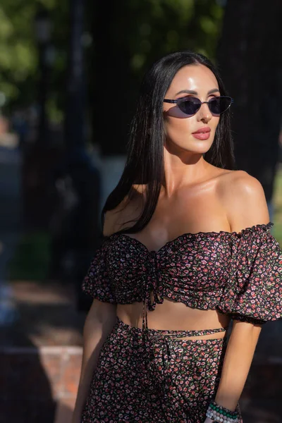 Hermosa joven en gafas en el parque sobre un fondo de vegetación. — Foto de Stock