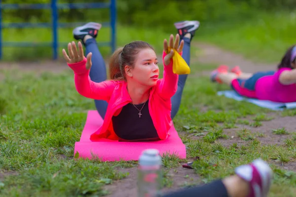 Ευτυχισμένη νεαρή γυναίκα κάνει κάποιες ασκήσεις τεντώματος στο πάρκο. — Φωτογραφία Αρχείου