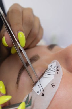 Güzellik salonunda uzun kirpikleri olan güzel bir kadın. Kirpik uzatma prosedürü. Kırbaçlar yakın..