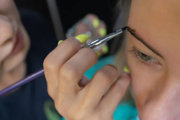 Kosmetikerin macht Enthaarung mit Wachsstreifen junge Frauen Augenbrauen im Wellnesszentrum. Attraktive Frau bekommt Gesichtsbehandlung im Schönheitssalon. — Stockfoto