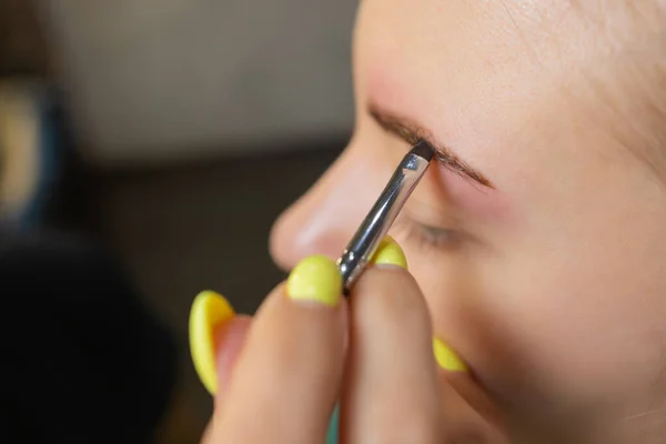 Kosmetikerin macht Enthaarung mit Wachsstreifen junge Frauen Augenbrauen im Wellnesszentrum. Attraktive Frau bekommt Gesichtsbehandlung im Schönheitssalon. — Stockfoto