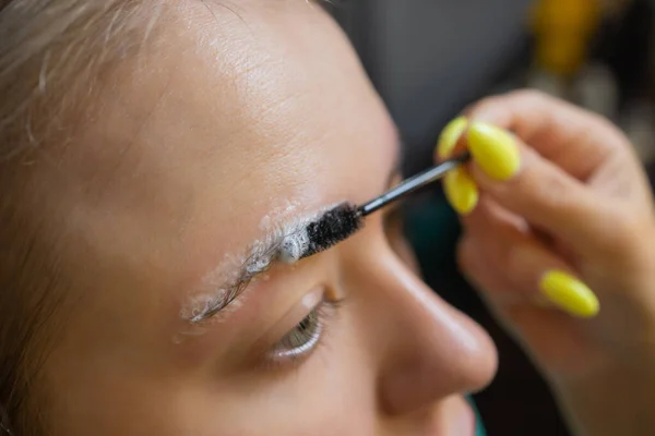 Kosmetikerin macht Enthaarung mit Wachsstreifen junge Frauen Augenbrauen im Wellnesszentrum. Attraktive Frau bekommt Gesichtsbehandlung im Schönheitssalon. — Stockfoto