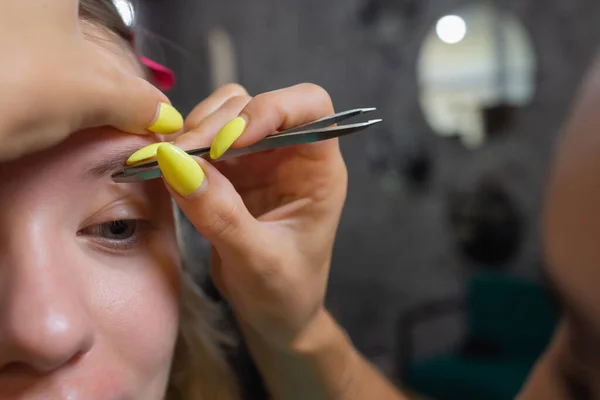 Beautician gör depilering med vaxremsa unga kvinnor ögonbryn i spa center. Attraktiv kvinna får ansiktsvård på skönhetssalong. — Stockfoto