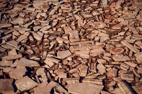 A look at the perspective of a surface covered with pieces of broken red brick.