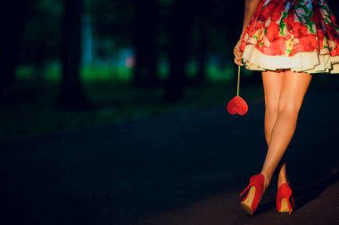 Sokak duvarının yanında, kırmızı yüksek topuklu ayakkabılı, kısa çizgili elbiseli şık bir kız..