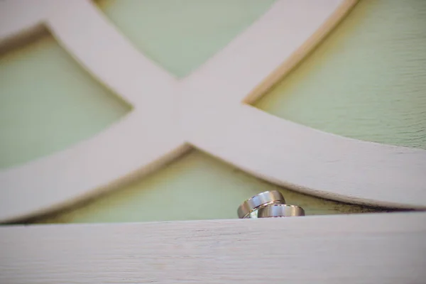 Par de anéis de casamento de ouro branco com diamantes no anel das mulheres. Pulseira de anéis de casamento de prata com pedras preciosas em fundo cinza minimalista com shaddows. — Fotografia de Stock