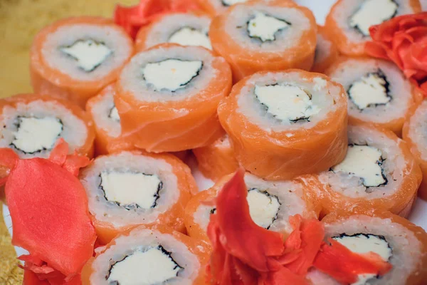 Gyönyörűen díszített sushi egy tányéron és evőpálcikák vannak a közelében. A sushi a hagyományos ázsiai és japán étel. Roll sushi nyers halból és egy különleges rizs. Egészséges táplálkozás. — Stock Fotó