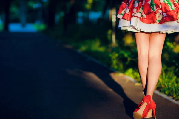 Outdoor fashionable girl near street wall legs in red high heel shoes and short striped dress. — Stock Photo, Image