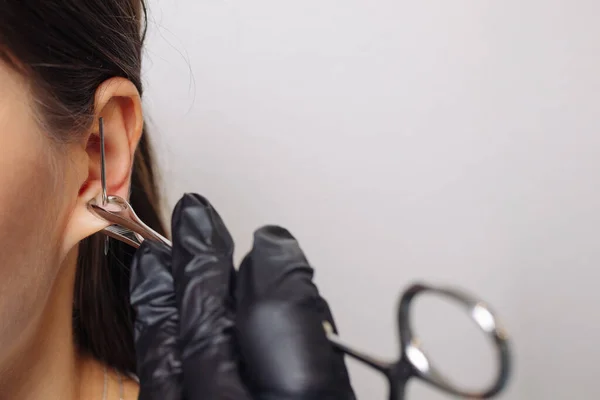 Profissional segurando a jóia de piercing pouco antes de parafusar a bola. — Fotografia de Stock