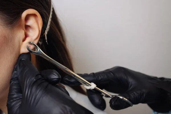 Profissional segurando a jóia de piercing pouco antes de parafusar a bola. — Fotografia de Stock