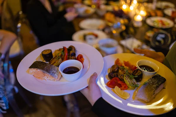 Дві м'ясні тарілки з листям салату та літній салат у руці офіціантів . — стокове фото