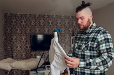 Bir adam işleri yoluna koyar. Buhar makinesini elinde tutuyor ve yıkadıktan sonra ceketi düzleştiriyor..