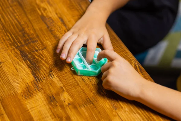 Criança brincando com pop-lo, pressionando as bolhas com os dedos, vista superior.Novo brinquedo antistress para crianças e adultos.Espaço de cópia para texto ou design. — Fotografia de Stock