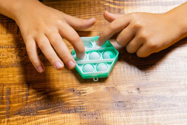 Criança brincando com pop-lo, pressionando as bolhas com os dedos, vista superior.Novo brinquedo antistress para crianças e adultos.Espaço de cópia para texto ou design. — Fotografia de Stock