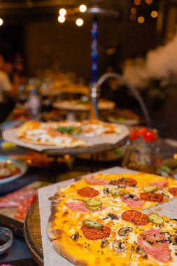 Sıcak pizza dilimi, erimiş peynirle ahşap bir masada..