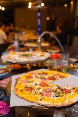 Sıcak pizza dilimi, erimiş peynirle ahşap bir masada..