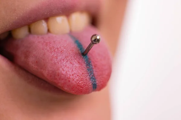 Närbild porträtt av ung kaukasisk kvinna sticker ut piercade tungan. — Stockfoto