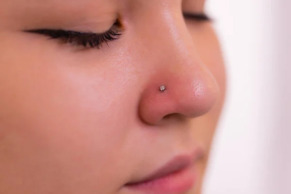 Primer plano de un rostro de mujer joven con piercing colgando de su nariz. — Foto de Stock