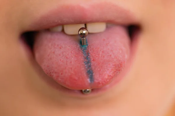 Primer plano retrato de la joven mujer caucásica sobresaliendo de la lengua perforada . Fotos De Stock