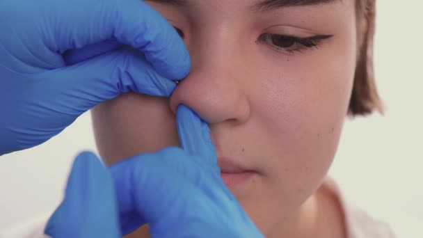 Close-up van een jonge vrouwen gezicht met piercing opknoping uit haar neus. — Stockvideo