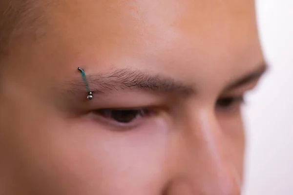 Man med piercade ögonbryn. Tre små svarta piercingar. — Stockfoto