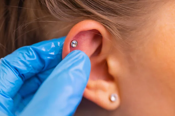 Profissional segurando a jóia de piercing pouco antes de parafusar a bola. — Fotografia de Stock