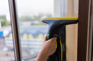 İş kıyafetleri içinde, evdeki profesyonel aletlerle pencereleri yıkayan güzel bir ev hanımı..