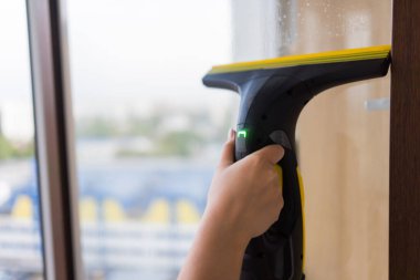 İş kıyafetleri içinde, evdeki profesyonel aletlerle pencereleri yıkayan güzel bir ev hanımı..