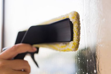 İş kıyafetleri içinde, evdeki profesyonel aletlerle pencereleri yıkayan güzel bir ev hanımı..