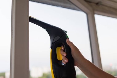 İş kıyafetleri içinde, evdeki profesyonel aletlerle pencereleri yıkayan güzel bir ev hanımı..