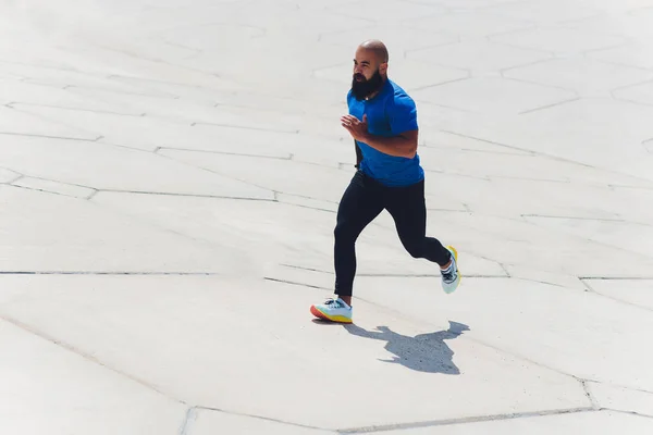 Młody sportowiec biegnie szybko na świeżym powietrzu. Ubrany w sportowy materiał, robi szeroki krok, demonstruje zdrowy styl życia, szerokie ujęcie. — Zdjęcie stockowe