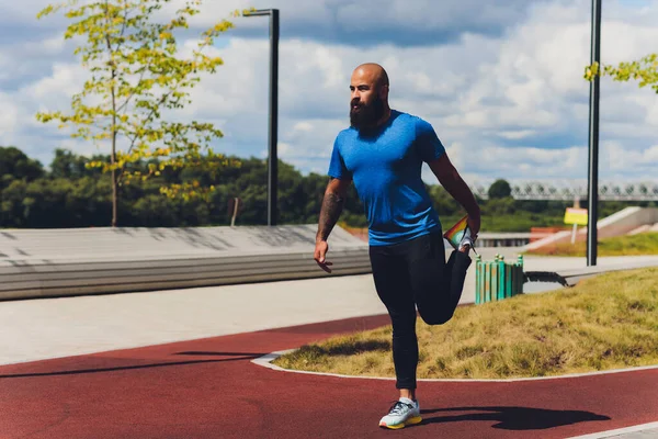 Młody sportowiec biegnie szybko na świeżym powietrzu. Ubrany w sportowy materiał, robi szeroki krok, demonstruje zdrowy styl życia, szerokie ujęcie. — Zdjęcie stockowe