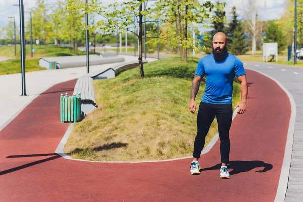 Młody sportowiec biegnie szybko na świeżym powietrzu. Ubrany w sportowy materiał, robi szeroki krok, demonstruje zdrowy styl życia, szerokie ujęcie. — Zdjęcie stockowe